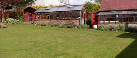 A residential property with a large lawn, a conservatory, and a detached house.