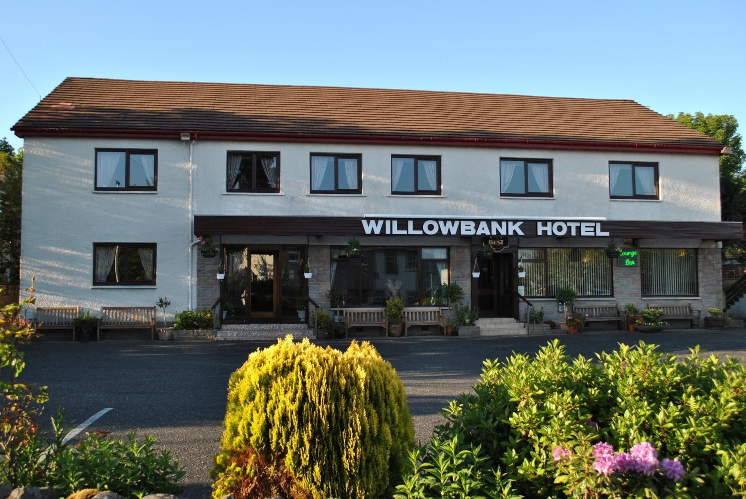 A two-story building with a sign reading 'Willowbank Hotel' above the entrance. There are multiple windows on the facade, and the building has a flat roof.