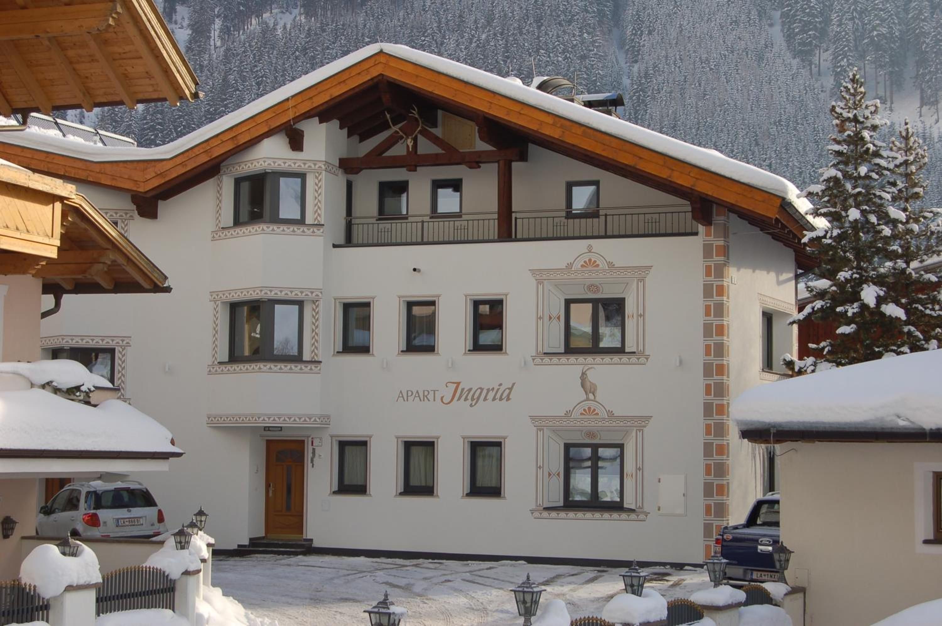 A multi-story building with a snow-covered roof and a sign that reads 'APART Ingrid.'