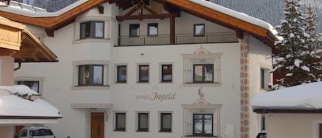 A multi-story building with a snow-covered roof and a sign that reads 'APART Ingrid.'