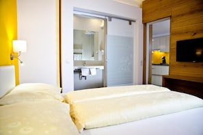 Una habitación de hotel con una cama, un baño con espejo y un televisor montado en la pared.