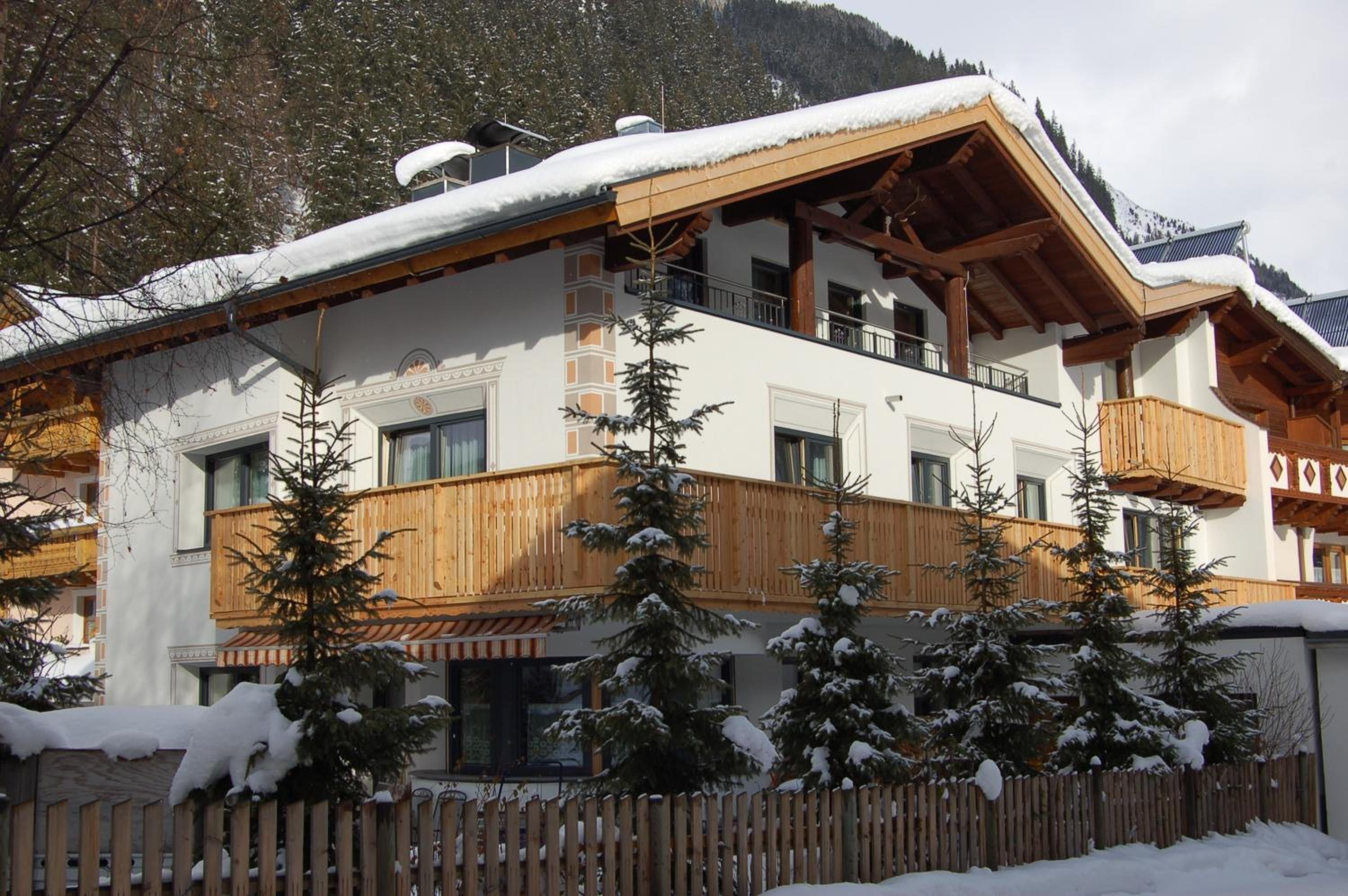 A multi-story building with a wooden facade, balconies, and snow-covered trees.
