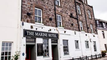 A traditional stone building with a sign for 'The Marine Hotel' indicating a restaurant and lounge bar.