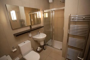 Un baño moderno con inodoro, lavamanos y ducha envuelta en vidrio.