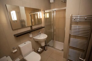 A modern bathroom with a toilet, sink, and glass-enclosed shower.