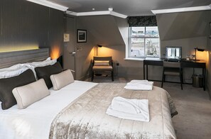 Habitación de hotel con cama, escritorio, silla y vistas al exterior.