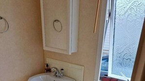 Ein kleines Badezimmer mit Waschbecken, Toilette und Fenster.