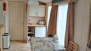 A compact living space with a kitchenette, a dining table, and a sofa.