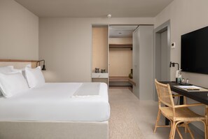 Une chambre d’hôtel avec un lit, un bureau, une chaise et un téléviseur.