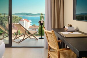 Una habitación con balcón, una mesa de comedor, una silla, una estantería y vistas al mar.