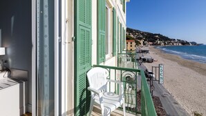 Ein Balkon mit einem weißen Stuhl, Blick auf den Strand und einem Hotelschild.