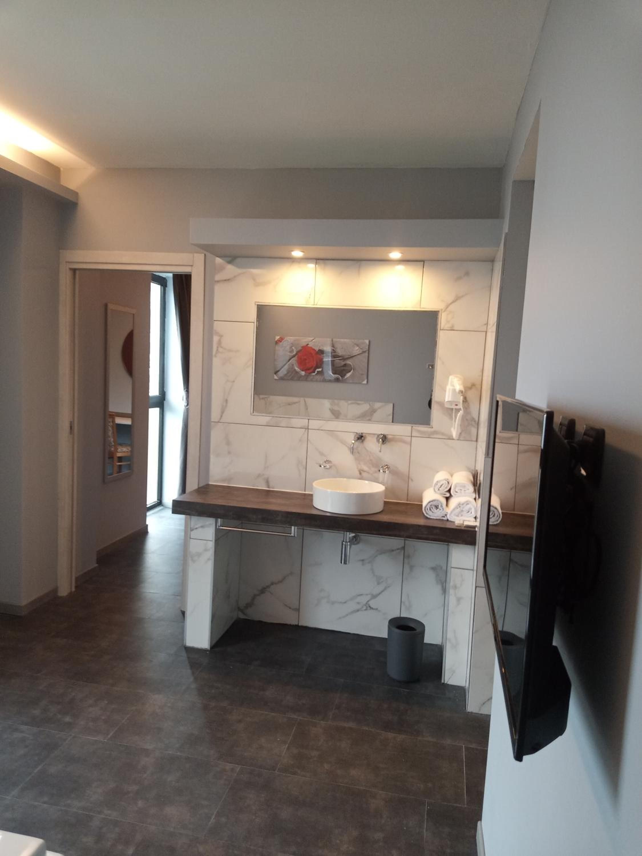 A modern bathroom with a marble sink, a towel rack, and a mirror.