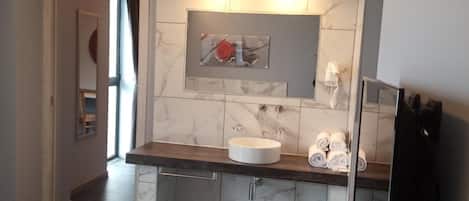 A modern bathroom with a marble sink, a towel rack, and a mirror.