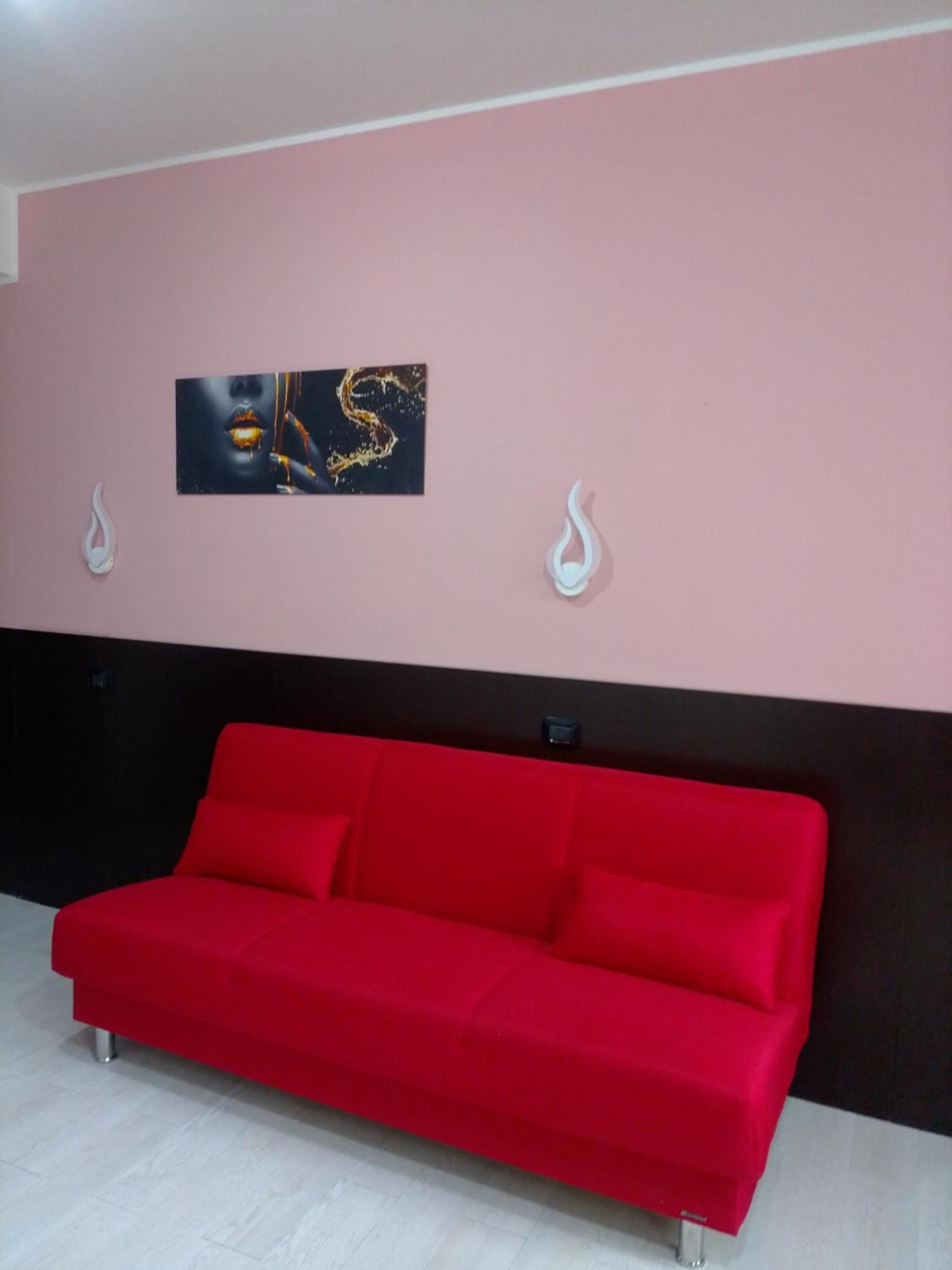 Ein rotes Sofa in einem Raum mit einer rosa Wand und einem schwarzen unteren Bereich.
