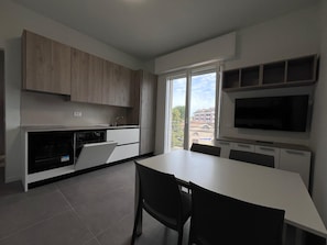 Una cocina moderna con comedor, ventanas amplias y televisor de pantalla plana.