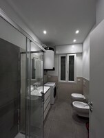 Un baño moderno con cabina de ducha de vidrio, lavamanos empotrado, inodoro y bidé.