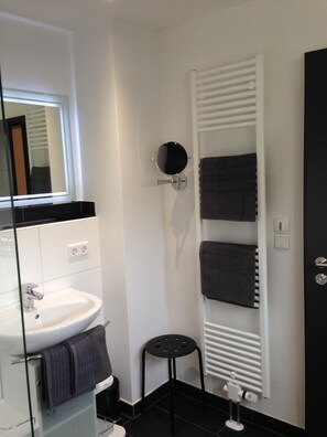 A bathroom with a white sink, a mirror, a towel rack, and a radiator. - Tankbar's Hotelchen (Heroldsberg)