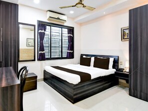A modern bedroom with a bed, bedside table, and a ceiling fan. - Classic Behala Urban Guest House (Alipur)