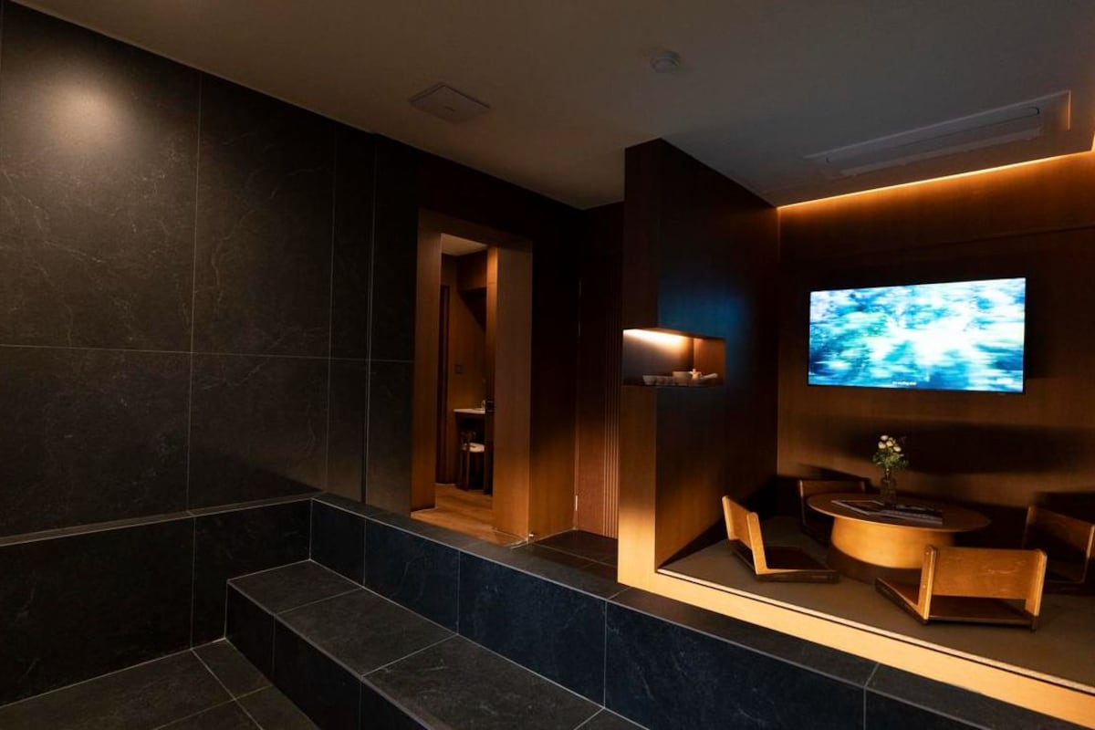 A modern lobby with a flat-screen TV, seating area, and a staircase.