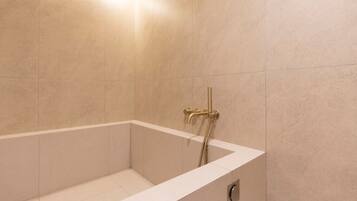 A modern bathroom with a freestanding bathtub, a showerhead, and a wall-mounted faucet.