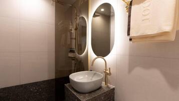 A bathroom with a white sink, gold fixtures, and a towel rack.