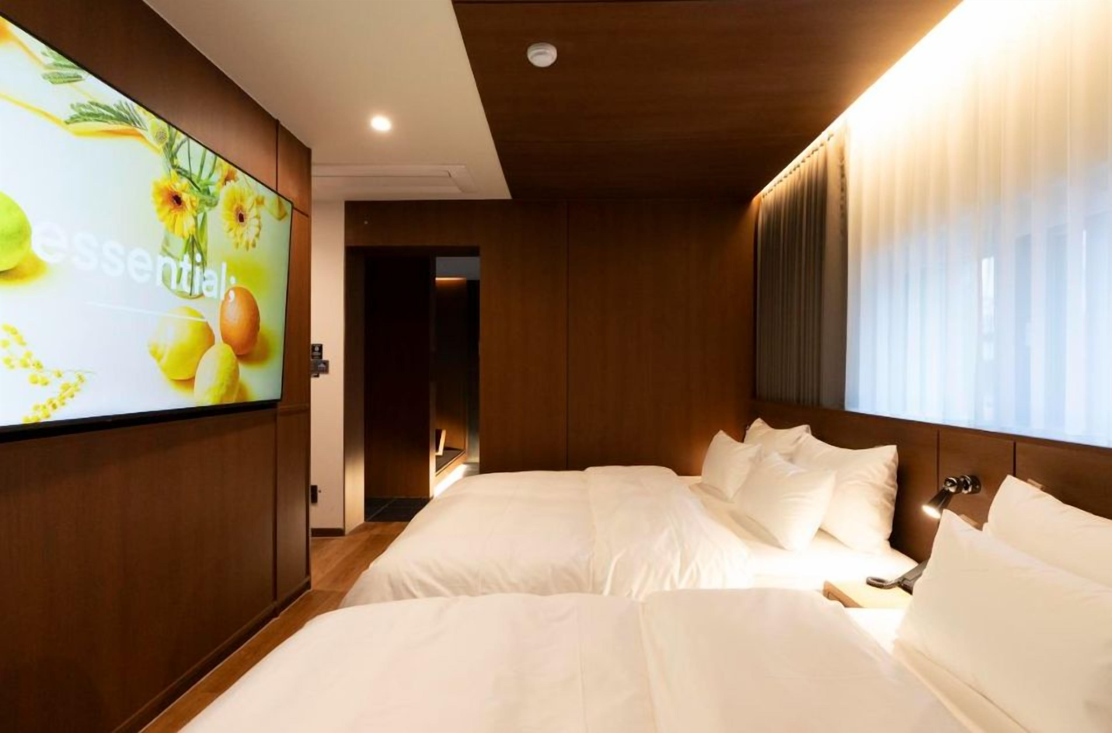 Una habitación de hotel con una cama grande, un televisor en la pared y una ventana con cortinas.