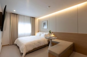 A hotel room with a bed, bedside table, and a seating area.