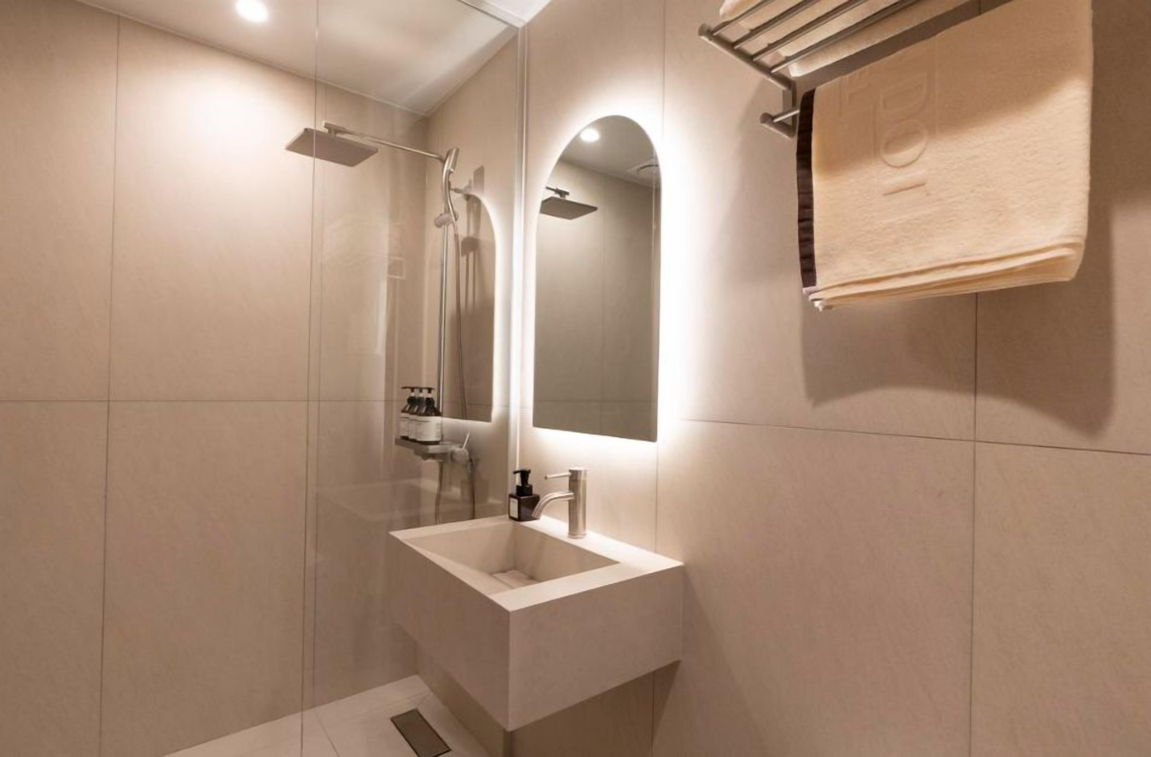 A modern bathroom with a glass-enclosed shower, a white sink, and a towel rack.