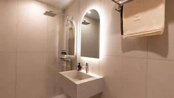 A modern bathroom with a glass-enclosed shower, a white sink, and a towel rack.