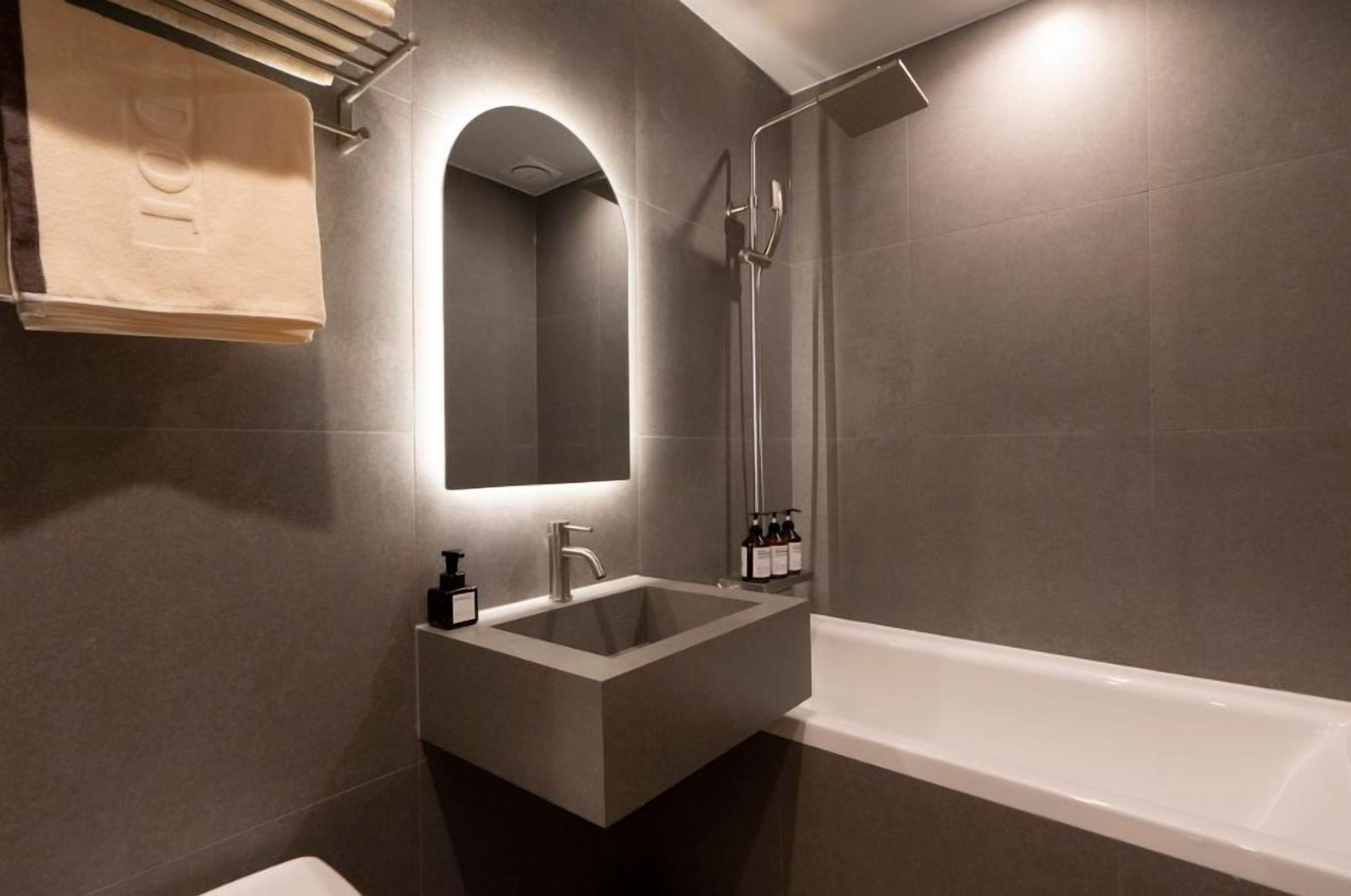 A modern bathroom with a built-in sink, a mirror, and a shower.
