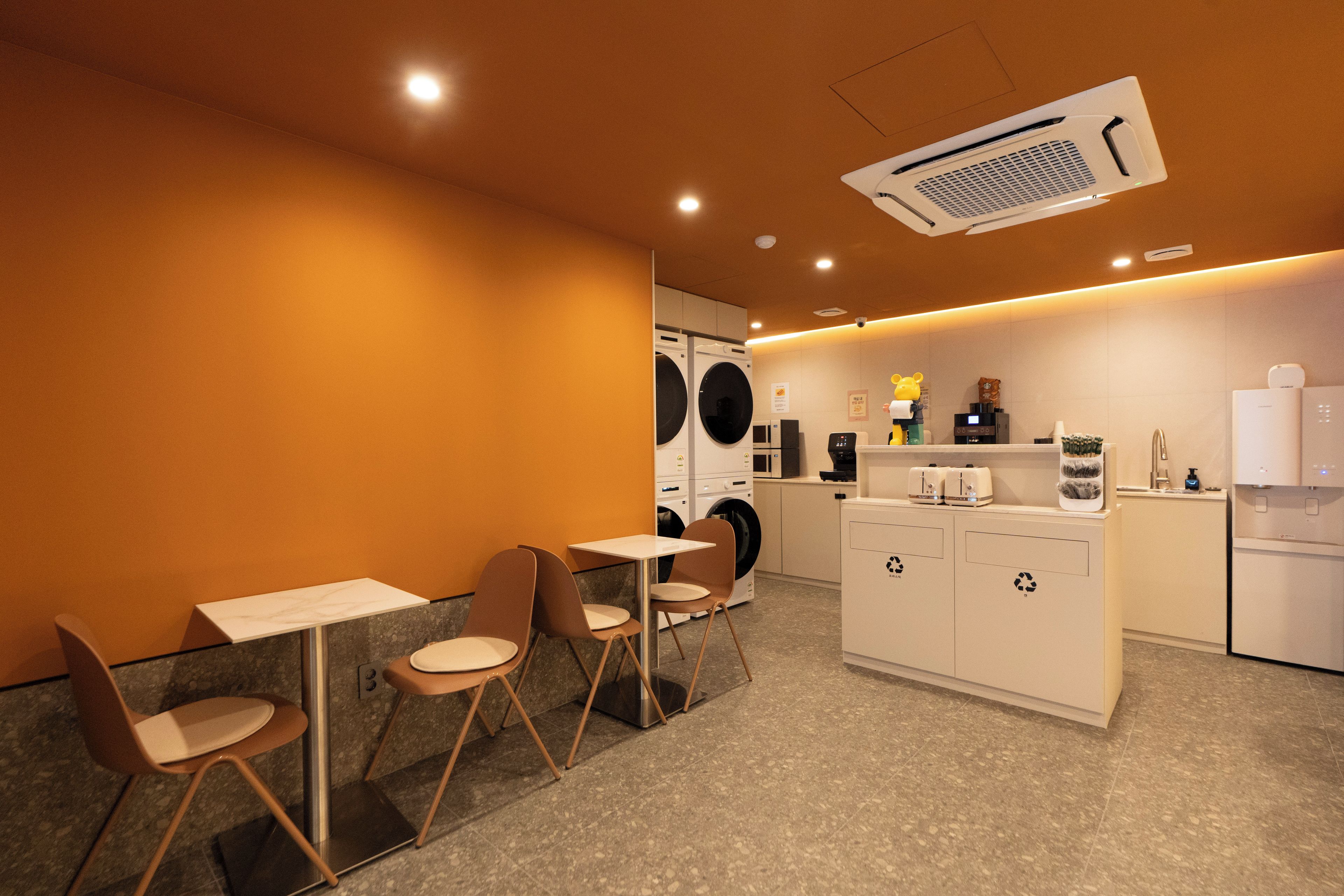 Un café moderno con zona de estar, una máquina de café y una lavadora.