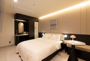 A modern bedroom with a large bed, bedside tables, a round table, and a mirror.