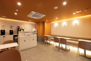 Ein modernes Café-Interieur mit Sitzgelegenheiten, einer Kaffeemaschine und einem Recyclingbehälter.