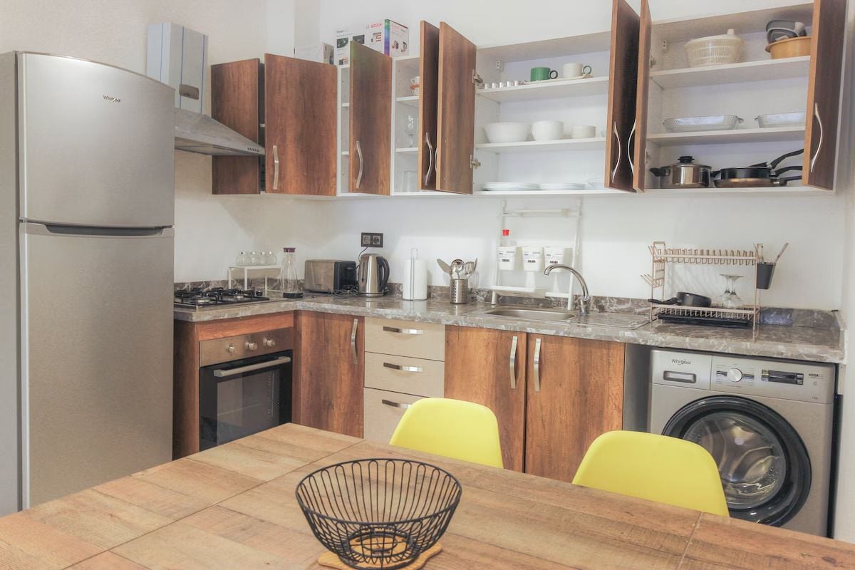 Eine kleine Küche mit Kühlschrank, Herd, Backofen und Waschmaschine.