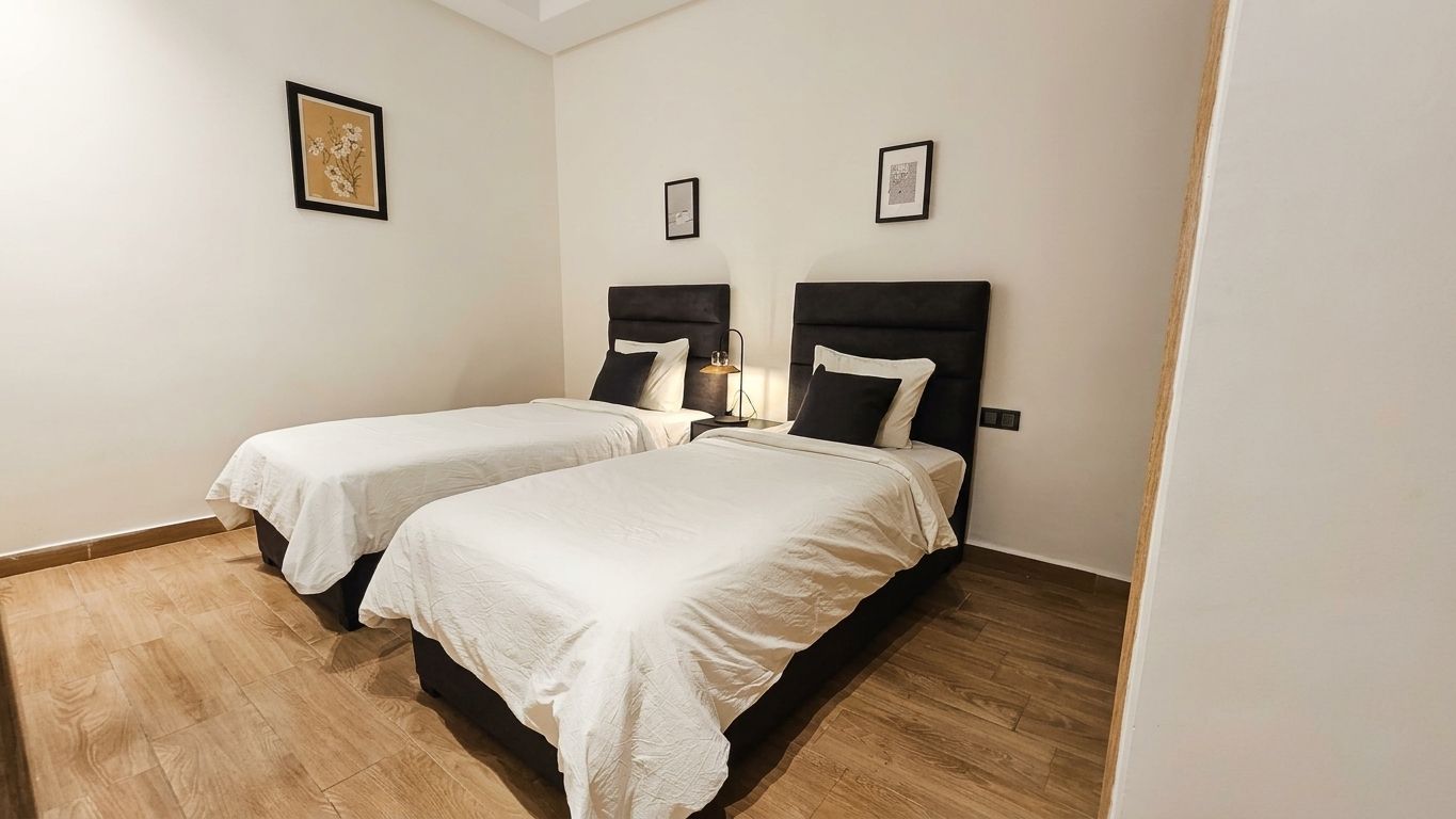 A room with two beds, each with a headboard and a pillow.