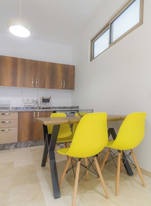 Une cuisine moderne avec des meubles en bois, une table à manger avec des chaises jaunes et un luminaire suspendu.