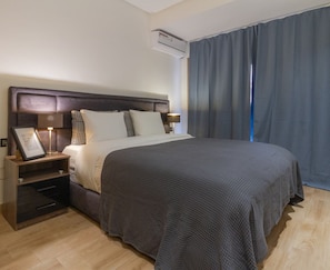 A hotel room with a large bed, bedside tables, an air conditioning unit, and a view of the outside through curtains. - Spacious 3-Bedroom Apartment • Pool, Balcony, and Free Parking (Marrakech)