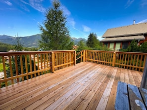 A wooden deck with a view of mountains and a house. - Cabin in Hohentauern With Sauna (Hohentauern)