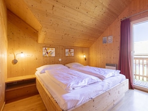 A wooden cabin bedroom with two beds, wooden walls, and a large window with curtains. - Cabin in Hohentauern With Sauna (Hohentauern)