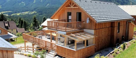 A wooden chalet with a balcony and a view of mountains.
