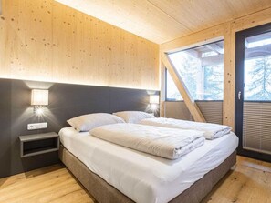 A bedroom with a bed, bedside tables, and a window with a view of trees. - Superior Chalet # 7 With Sauna & Hot Tub (Stadl-Predlitz)