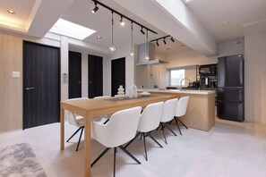A modern kitchen with a central island, white chairs, and a dining table. - eni.taniroku (Osaka)