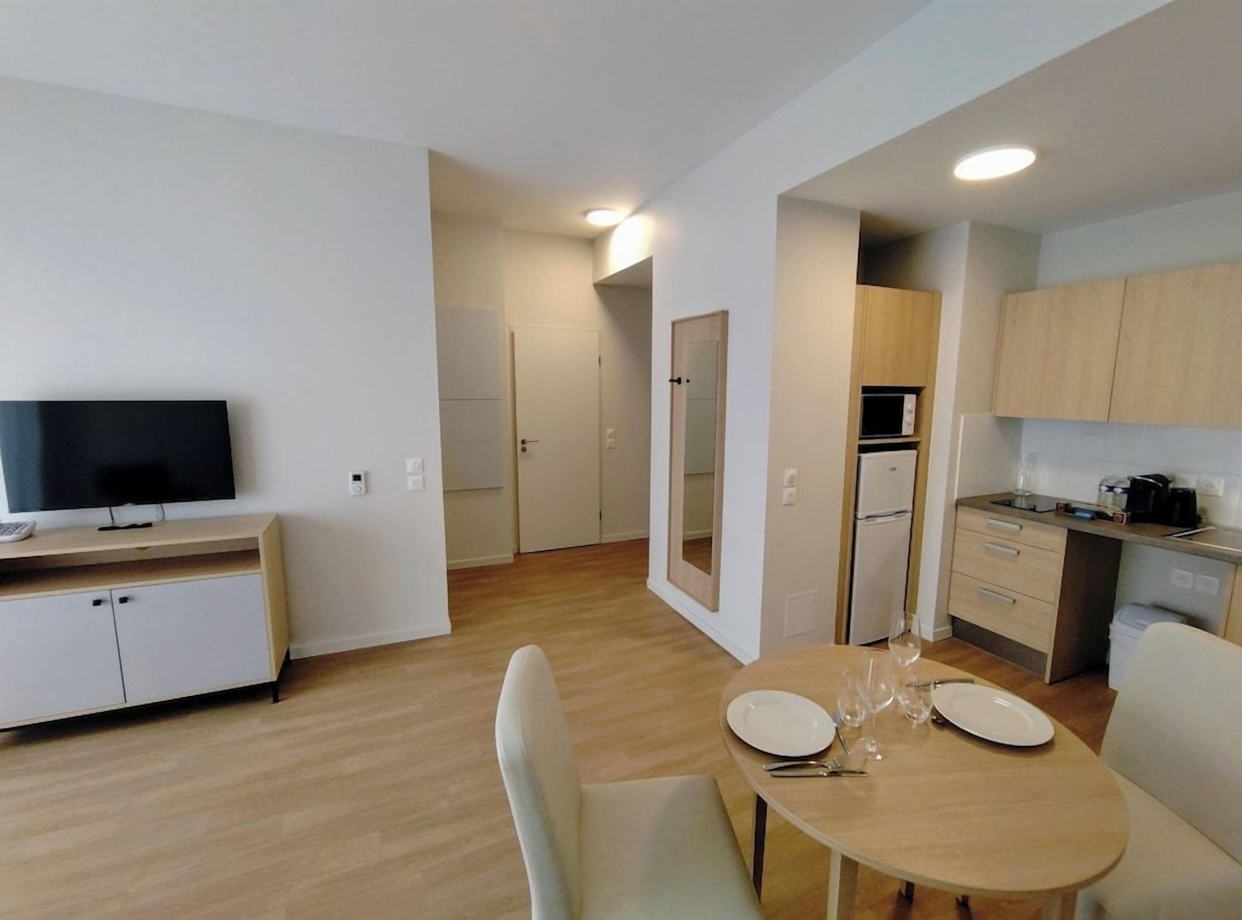 A modern kitchen with a dining area, a television, and a microwave.