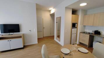 A modern kitchen with a dining area, a television, and a microwave.