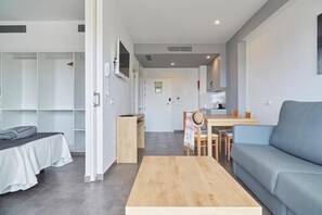 Una sala de estar moderna con sofá, una mesa de centro, un comedor con mesa y sillas, una cocina al fondo y un vestidor con estantes.