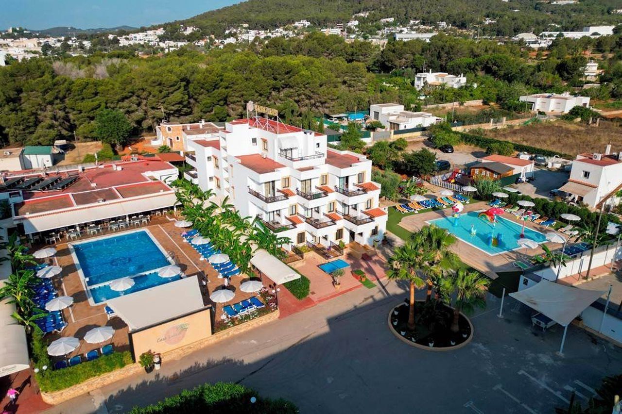 A resort with multiple buildings, a swimming pool, and a landscaped area with palm trees.