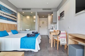 Una habitación de hotel con una cama, un escritorio, una silla y una mesita.
