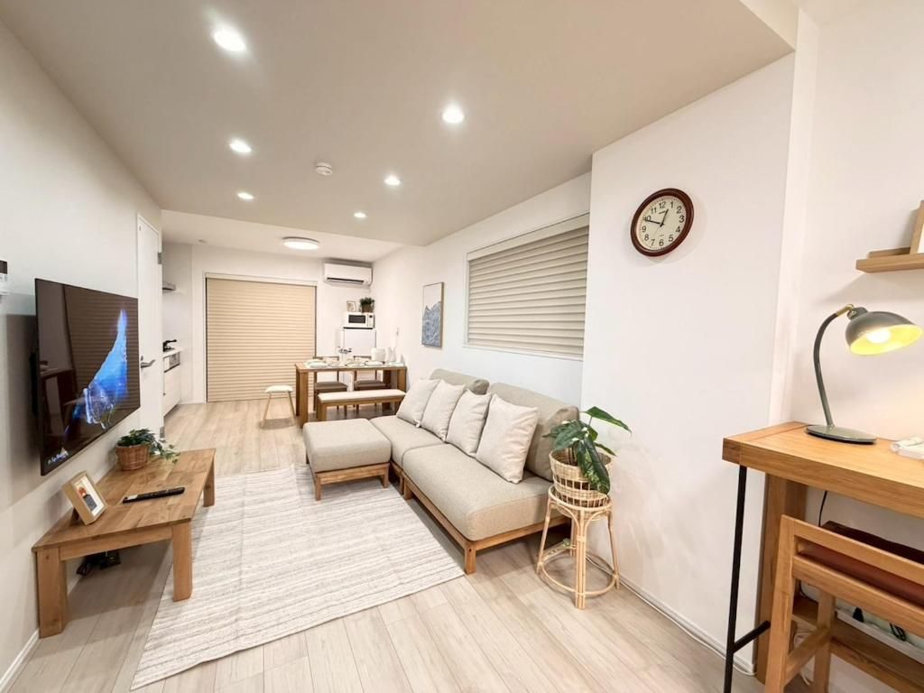 A modern living room with a sofa, a coffee table, a TV, and a dining area with a table and chairs.
