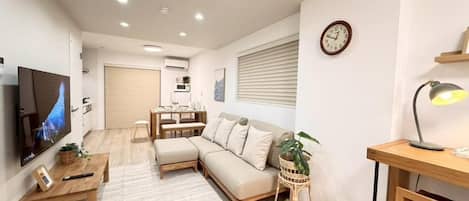 A modern living room with a sofa, a coffee table, a TV, and a dining area with a table and chairs.