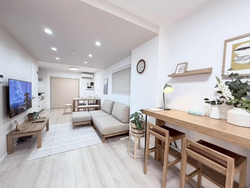 Una sala de estar moderna con un sofá, una mesa de centro de madera, un televisor y un escritorio con una lámpara.